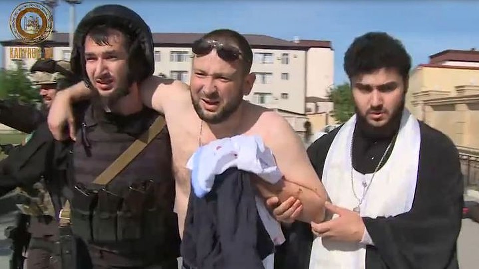 Собровец и священник выводят из храма раненного в грудь врача Федора Напольникова.