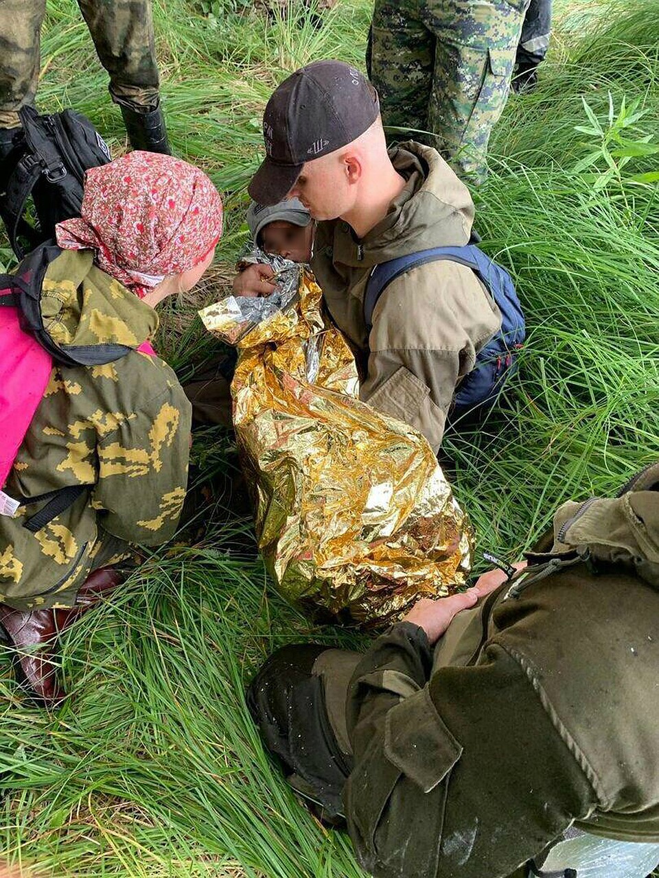 Спасенного мальчика завернули в специальное одеяло, сохраняющее тепло. Предстоял долгий путь обратно по топям. Фото: Евгений Мотовилов