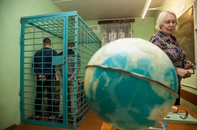 Парты, за которыми занимаются ученики, находятся за железными решетками.