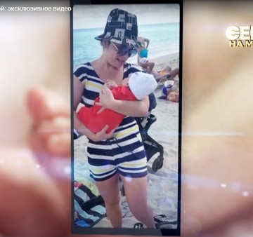 В студии показали снимки трогательного момента первой встречи мамы с двухмесячной дочкой. На фото Наташа, одетая в полосатый пляжный комбинезончик и в панамку с графическим принтом, держит дочь на руках. Фото: кадр видео.
