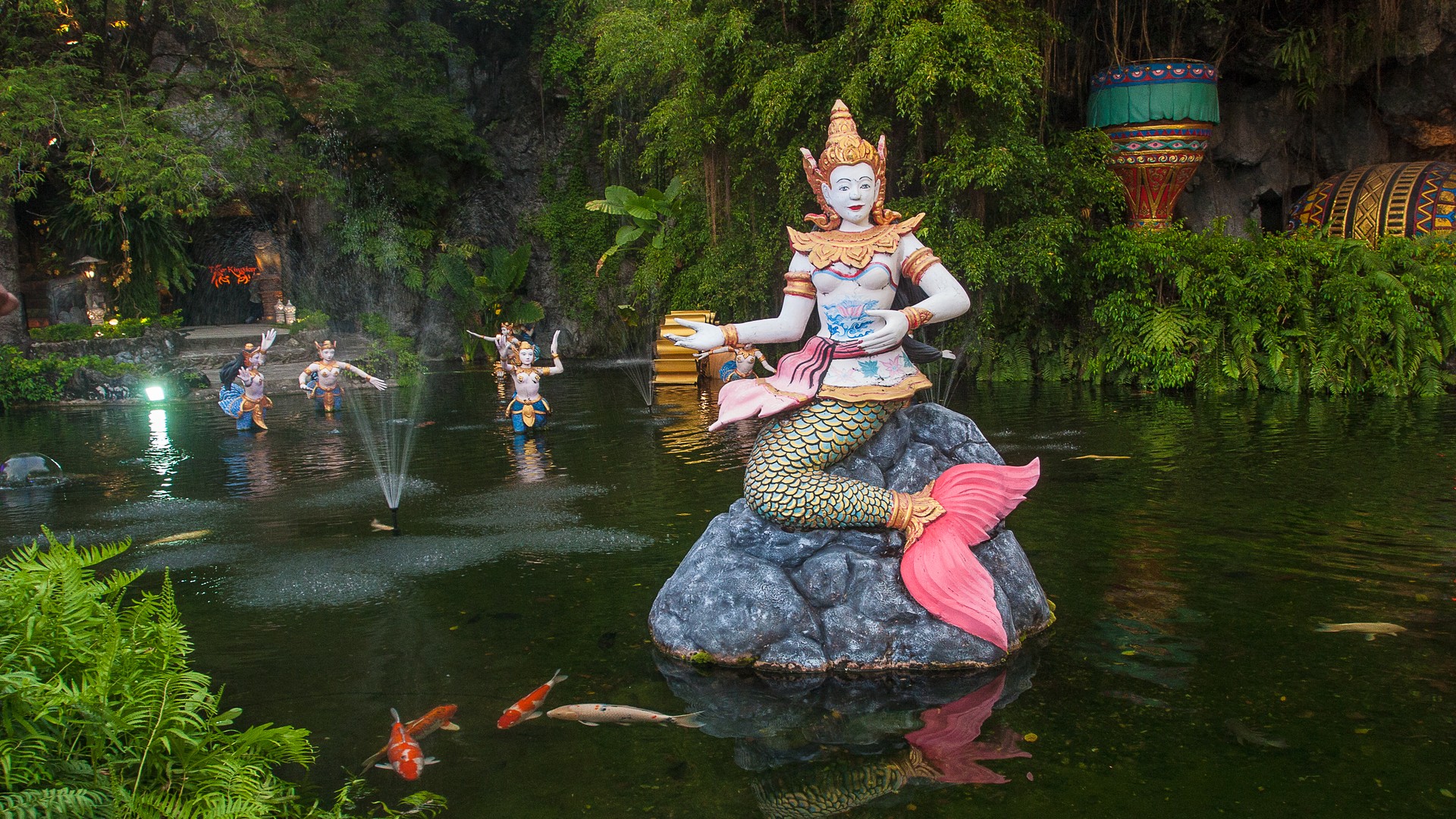 Сказочные фигуры, фонтаны и рыбы в пруду, тематический парк Phuket FantaSea.